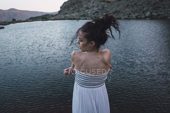 Young woman in elegant dress standing near rippling lake — Stock Photo