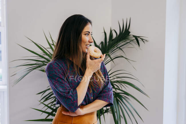 Femme gaie avec beignet au bureau — Photo de stock