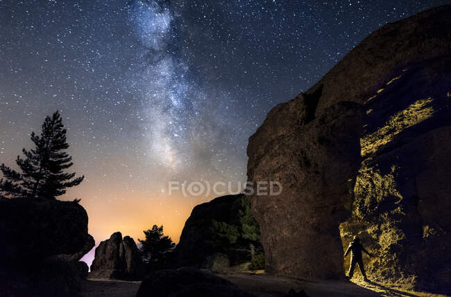Silhouette eines Mannes in der Nacht bei der Erkundung einer Höhle im Berg mit einer Fackel unter einer erstaunlichen Milchstraße. soria, Spanien — Stockfoto