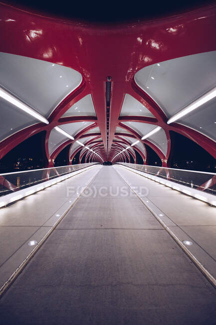 Perspective view of modern construction of pedestrian bridge illuminated in dark night, Canada — Stock Photo