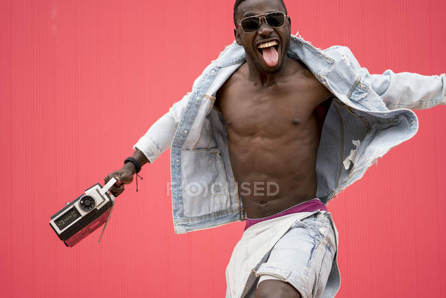 African american man dancing with vintage radio device on red background — Stock Photo