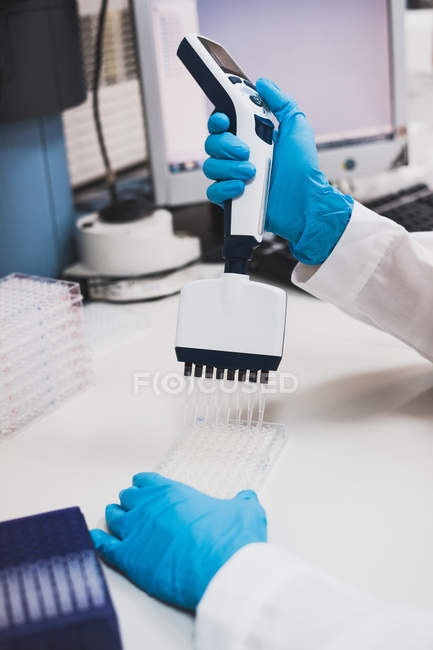 Manos de la persona en guantes de goma azul utilizando equipo de laboratorio - foto de stock