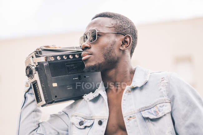 Black man in sunglasses walking with vintage radio device — Stock Photo