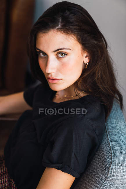 Giovane donna bruna sensuale seduta in poltrona e guardando la fotocamera — Foto stock