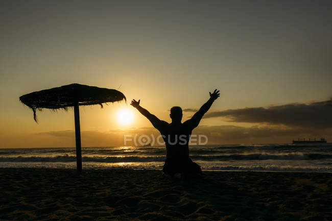 Forte vecchio in posa sulla spiaggia con le mani in alto — Foto stock