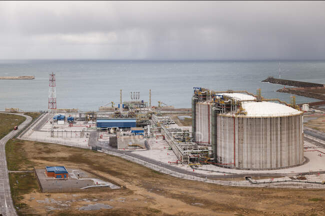 Зверху на заводську територію з будівлями та обладнанням, розміщеними біля блакитного моря — стокове фото