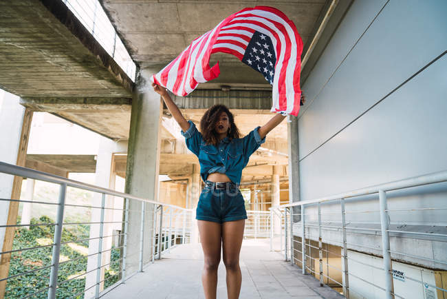 Афро-американських молода жінка стоїть на вулиці з прапором США і дивлячись на камеру — стокове фото