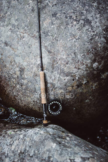 Fisherman spinning is leaning against the stone — Stock Photo