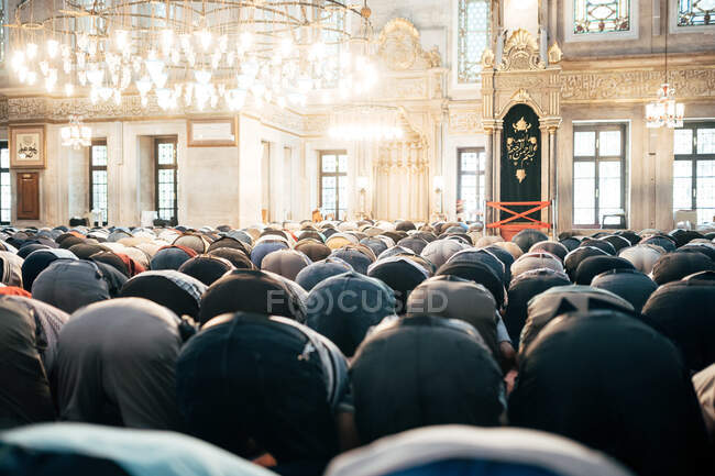 Vista posterior de oraciones masculinas irreconocibles sentadas en la mezquita durante el ritual - foto de stock