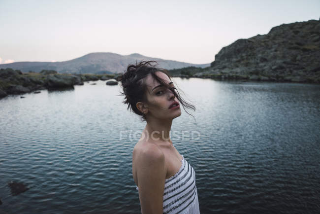 Jeune femme debout près du lac ondulant et regardant la caméra — Photo de stock
