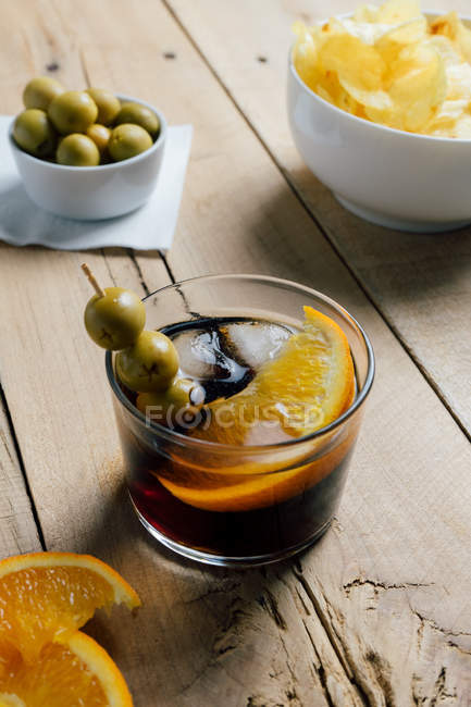 Cóctel y aperitivos servidos en mesa de madera - foto de stock