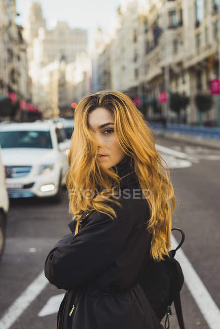 Jeune femme posant sur la route en ville — Photo de stock
