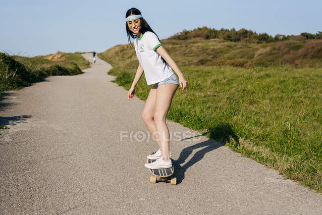 Trendy teen girl riding board on road — Stock Photo