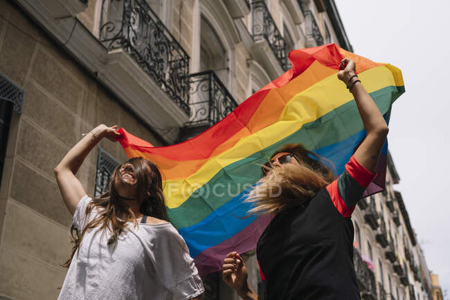 Coppia donna lesbica con bandiera gay orgoglio sulla strada della città di Madrid — Foto stock