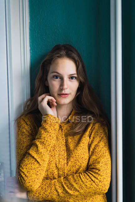 Porträt einer jungen hübschen Frau, die an der Wand steht und in die Kamera blickt — Stockfoto