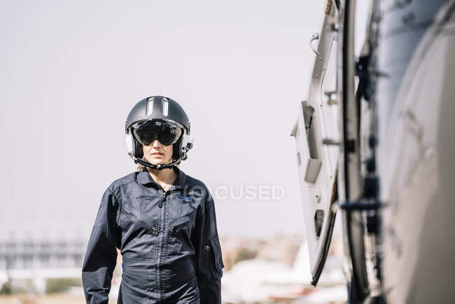 Пілот дівчина позує зі своїм гелікоптером і шоломом — стокове фото