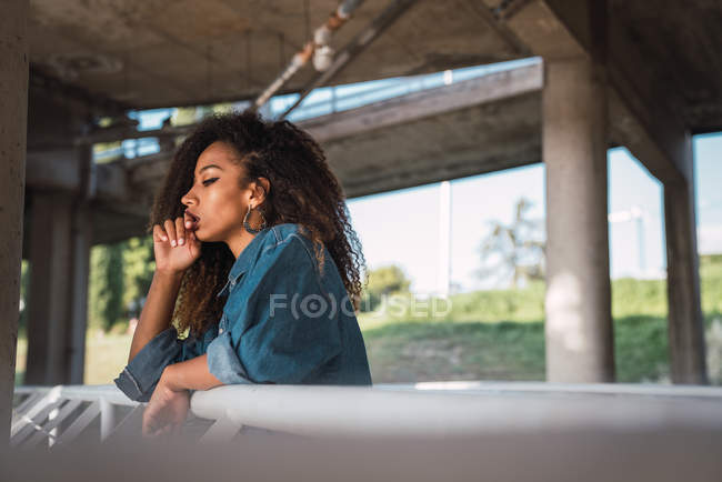 Young thoughtful woman standing at balcony near railing — Stock Photo
