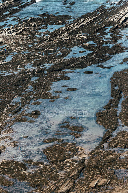 De cima tiro de água azul cobrindo superfície pedregosa áspera no dia ensolarado no campo — Fotografia de Stock