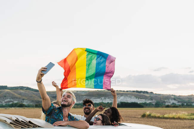 Pessoas com bandeira LGBT em van tirando selfie — Fotografia de Stock