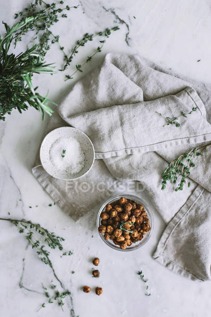 Roasted chickpeas in glass jar on white marble surface — Stock Photo