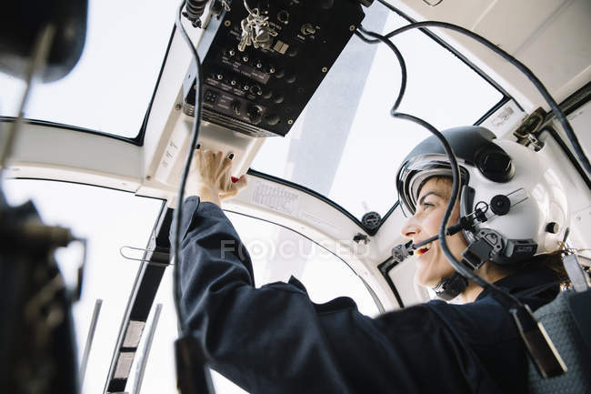 Pilota donna sorridente seduta in elicottero e operante — Foto stock