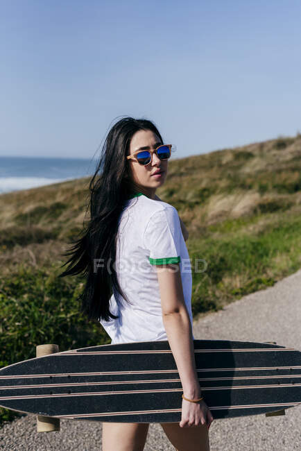 Pretty girl with long board on road — Stock Photo