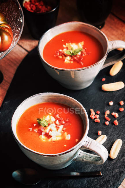 Tomaten Gazpacho serviert mit Ei und Schinken in Tassen auf Schiefer — Stockfoto