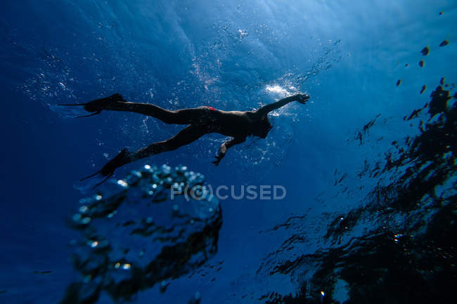 Силуэт сноркелинга человека в темной морской воде — стоковое фото