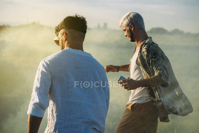 Los hombres caminando a través de humo en el campo - foto de stock