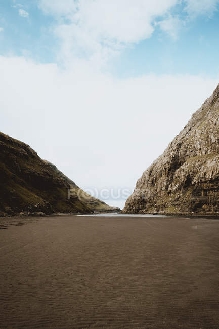 Beach and rocky cliffs at calm ocean on Feroe Islands — Stock Photo