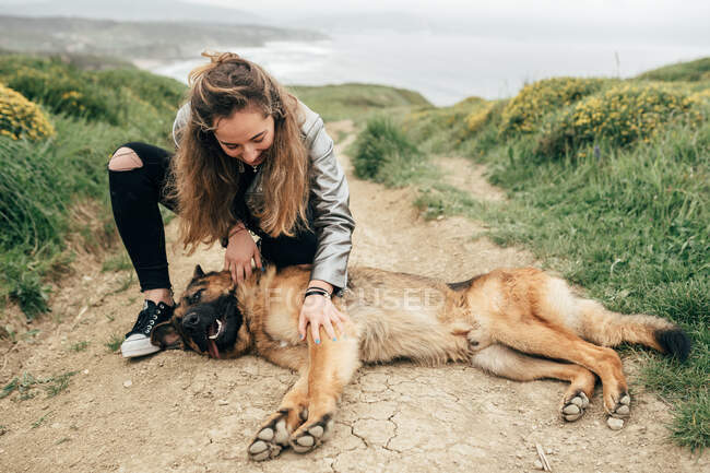 Young woman petting dog in nature — Stock Photo