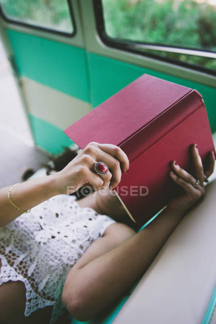 Женщина лежит внутри ретро-каравана и читает книгу — стоковое фото