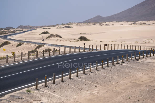 Estrada e vegetação estéril no deserto de Fuerteventura, Ilhas Canárias — Fotografia de Stock