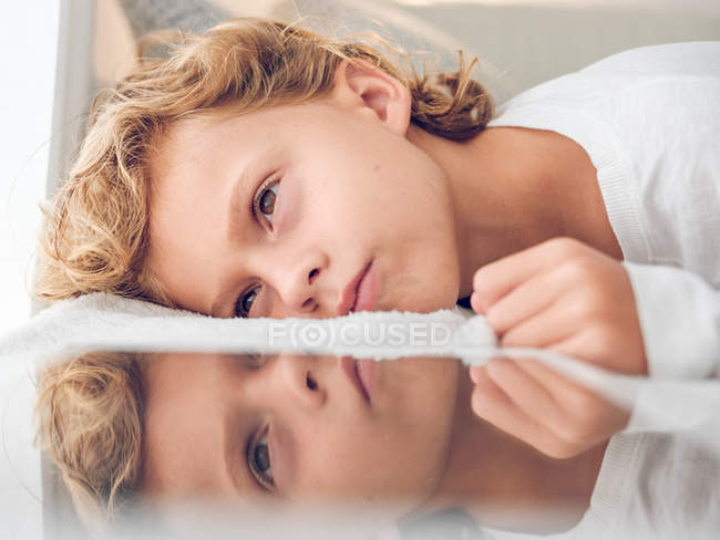 Gros plan de garçon ennuyé couché près de tablette numérique — Photo de stock