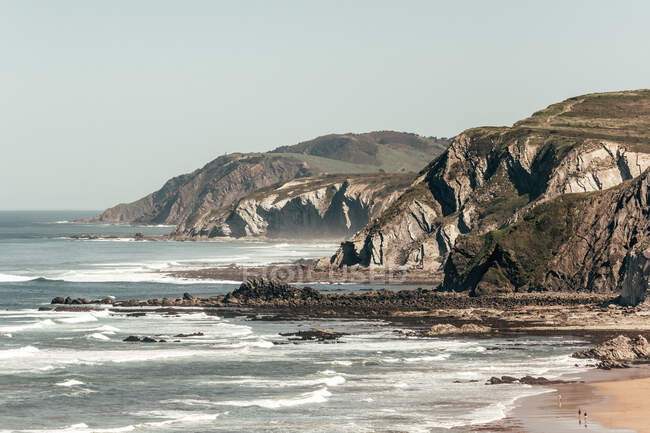 Vista magnífica do mar incrível com ondas rolantes e penhascos rochosos no fundo do céu cinza — Fotografia de Stock