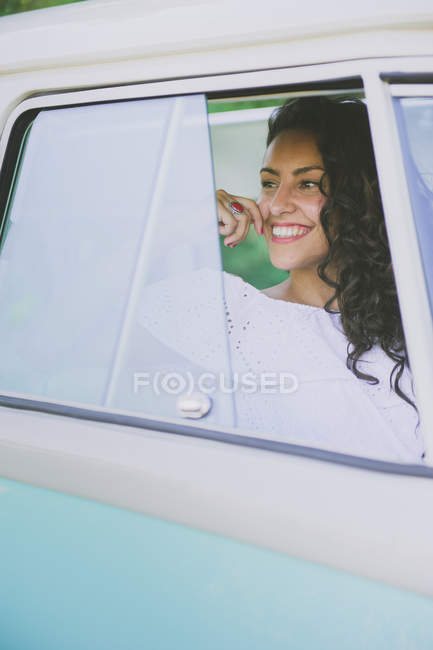 Joyeux jeune femme regardant loin dans la voiture — Photo de stock