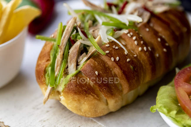 Primer plano de sándwich grande con verduras y pollo en la mesa gris - foto de stock