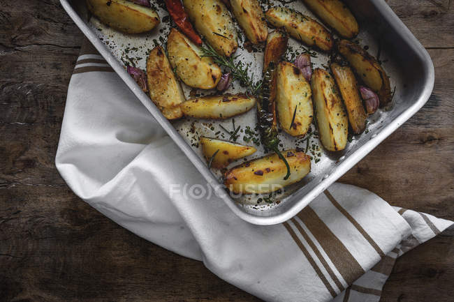 Gebratene goldene knusprige Kartoffelkeile in Backform auf Holztisch — Stockfoto