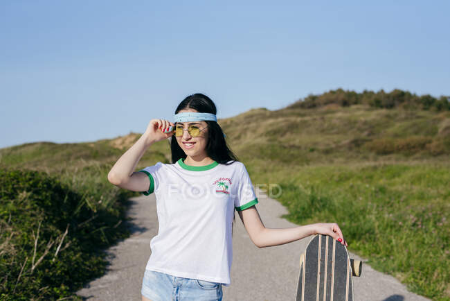 Elegante chica adolescente con tablero largo en verano - foto de stock