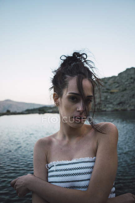 Giovane donna in piedi vicino al lago increspatura e guardando la fotocamera — Foto stock