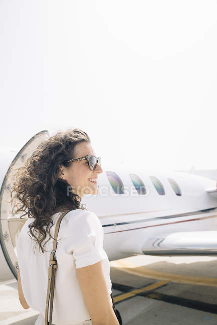Улыбающаяся женщина-путешественница, вылетающая из самолета по прибытии в аэропорт — стоковое фото