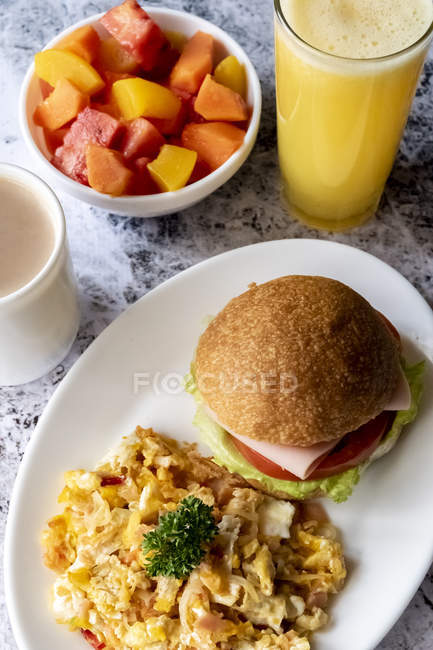 Hamburger and omelette on plate served with fruits and juice — Stock Photo