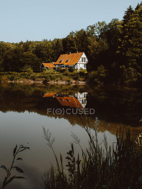 Casa grande com telhado laranja construído na floresta e lagoa em Feroe Island — Fotografia de Stock