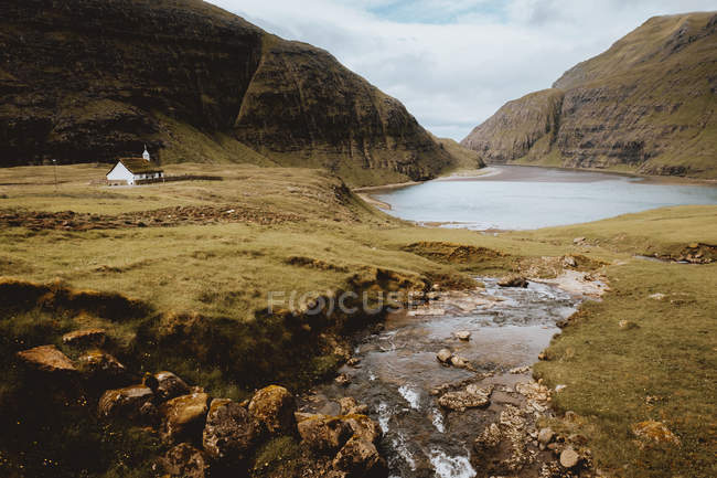 Solitario casetta in verdi montagne al lago in nuvoloso, Isole Feroe — Foto stock
