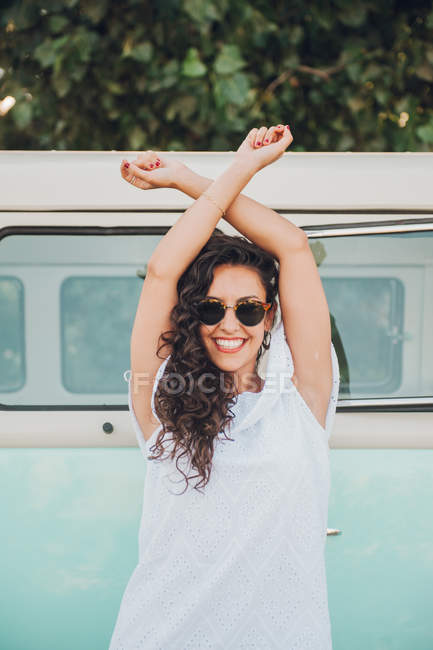 Веселая брюнетка в солнцезащитных очках позирует возле фургона — стоковое фото