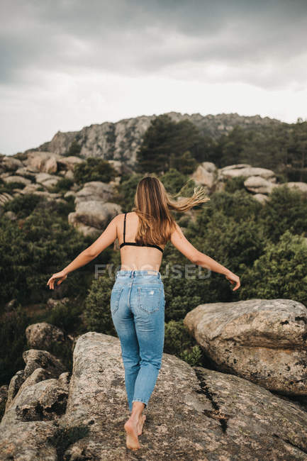 Женщина в лифчике стоит на скалах — стоковое фото
