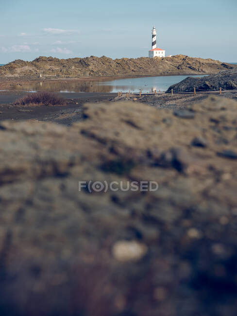 Vista para a costa rochosa e torre do farol à beira-mar. — Fotografia de Stock