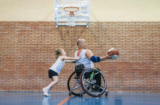 Disabled sport men and little girl in action while playing indoor basketball — Stock Photo