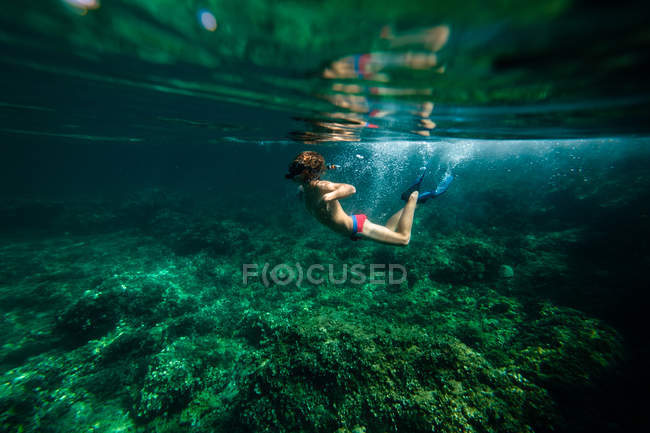 Garçon méconnaissable plongeant dans l'eau de mer — Photo de stock