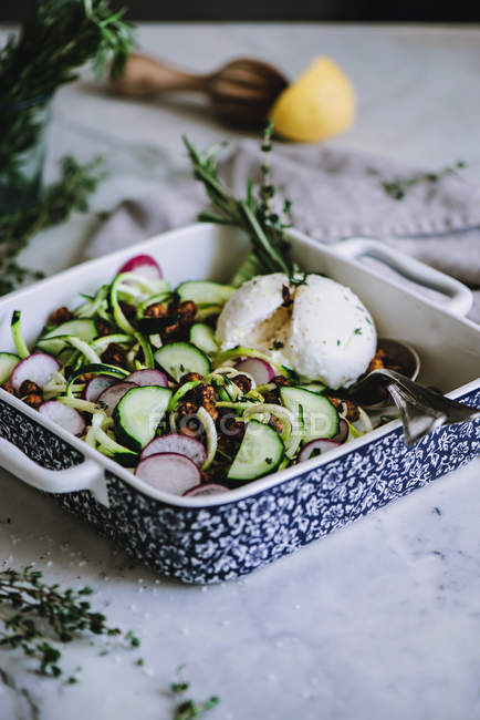 Zucchini salad in patterned dish with spoon and fork — Stock Photo